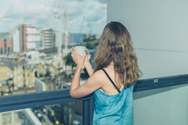Frau mit Tasse Kaffee auf Balkon in der Stadt — Stockfoto