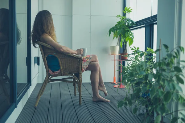 Vrouw in rieten stoel op balkon — Stockfoto