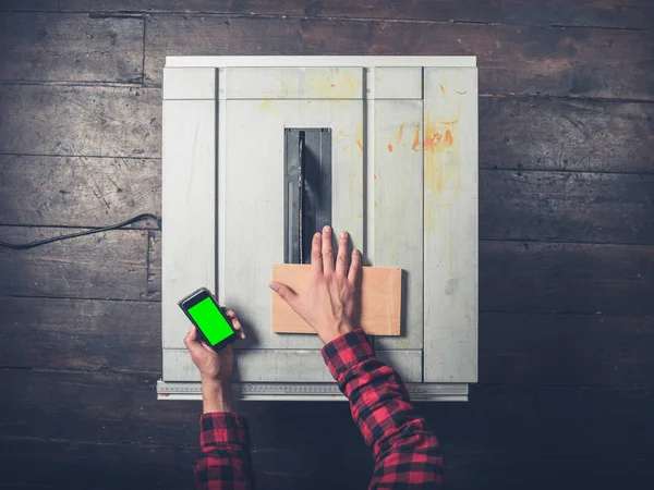 Man with chroma key smart phone and tablesaw