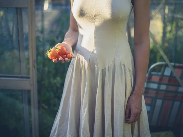 Vrouw in jurk met tomaten in de serre — Stockfoto