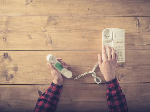 Hombre en la mesa haciendo una llamada con teléfono viejo — Foto de Stock