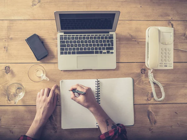 Over view of man at desk writing in notepad — Stock Photo, Image