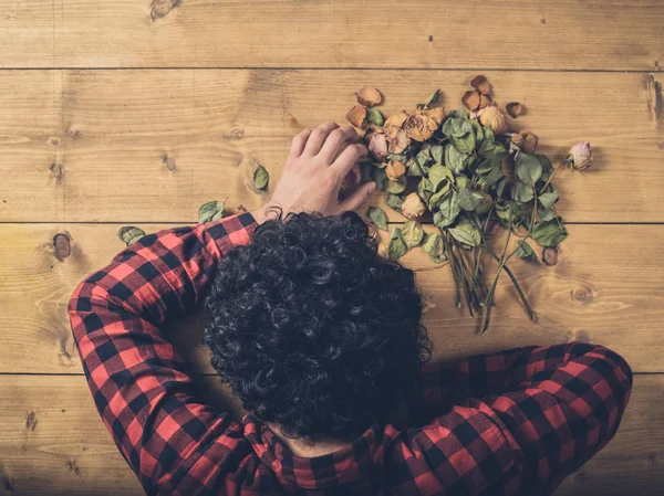 Λυπημένος άνθρωπος με νεκρά λουλούδια στο πάτωμα — Φωτογραφία Αρχείου