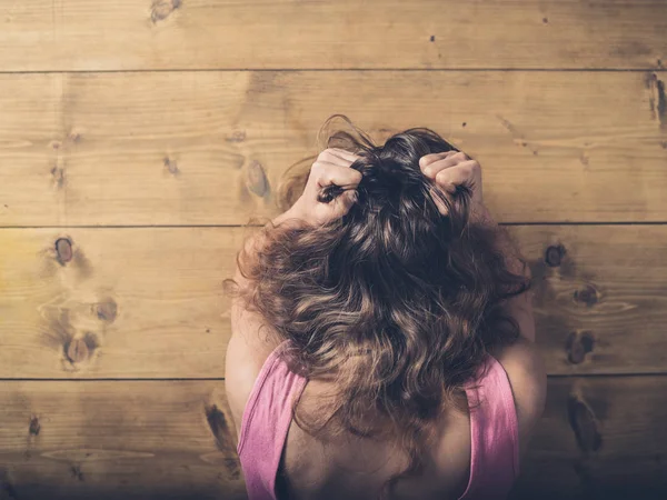 Vrouw aan tafel trekken van haar haren in frustratie — Stockfoto