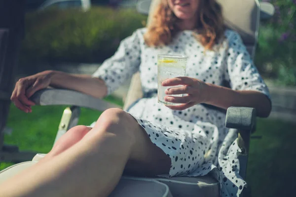 Vrouw drinken uit glas in de ligstoel — Stockfoto