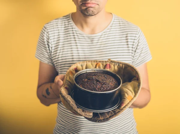 Junger Mann mit verbranntem Kuchen beunruhigt — Stockfoto
