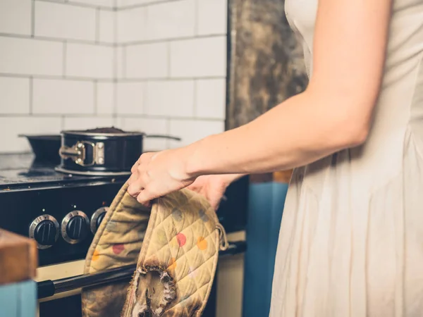 Femme dans la cuisine avec gâteau brûlé et gants de four — Photo