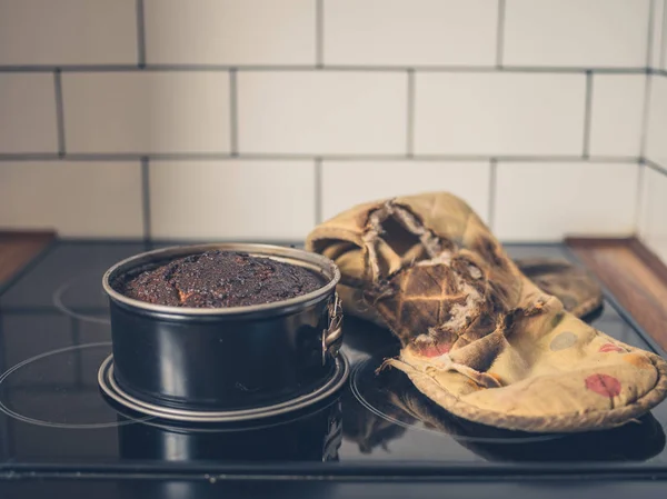 Burnt cake and oven glove on cooker