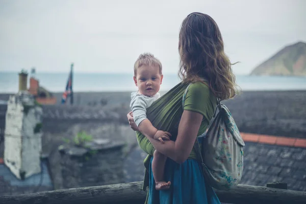 Moeder met baby kijken naar stad en de zee — Stockfoto