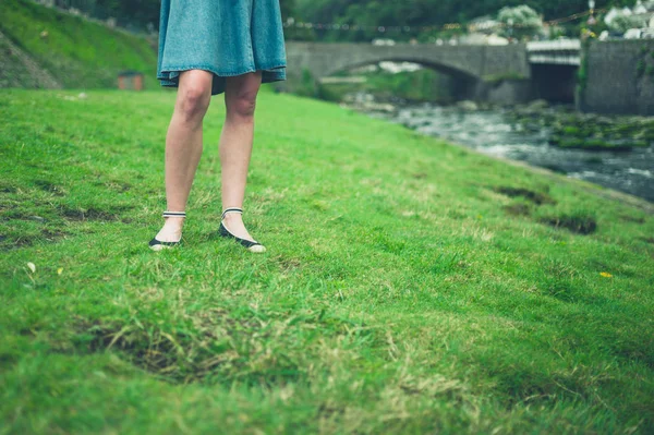 Benen på unga kvinna som står vid floden — Stockfoto