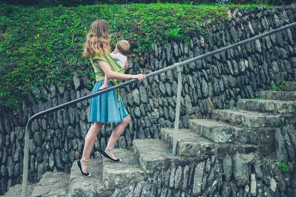Мать с ребенком в стропе ходить вверх по ступенькам в природе — стоковое фото