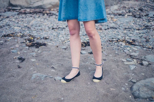 Jambes et pieds de jeune femme debout sur la plage — Photo