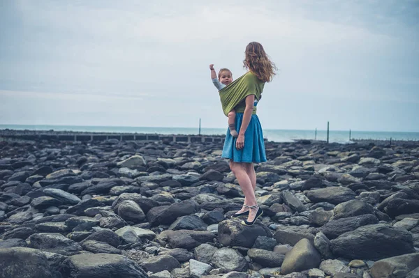 Madre con bebé en cabestrillo en la playa en otoño — Foto de Stock