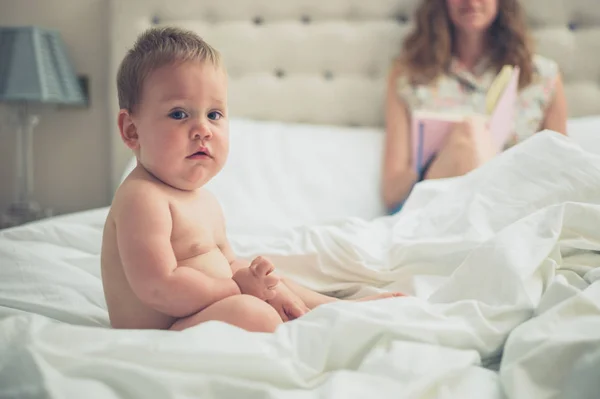 Madre en la cama con la lectura del bebé del diario —  Fotos de Stock