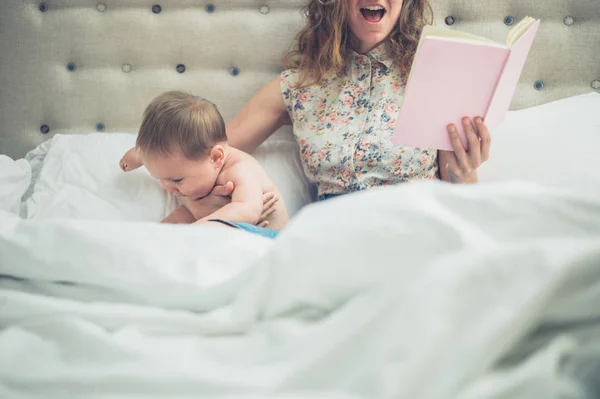 Mutter im Bett liest ihrem aufgeregten Baby vor — Stockfoto