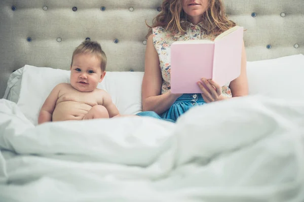 Mãe na cama lendo para seu bebê — Fotografia de Stock