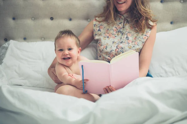 Giovane madre a letto a leggere al suo piccolo bambino — Foto Stock