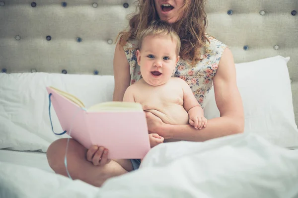 Junge Mutter liest ihrem kleinen Baby im Bett vor — Stockfoto