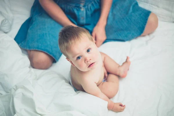 Mãe e bebê sentados na cama — Fotografia de Stock