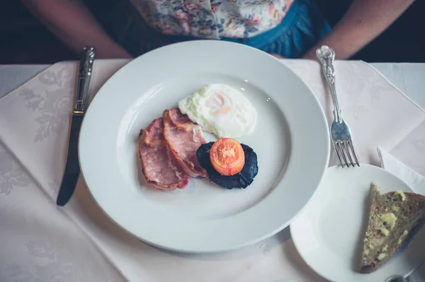 Mulher tomando café da manhã de ovos e bacon — Fotografia de Stock