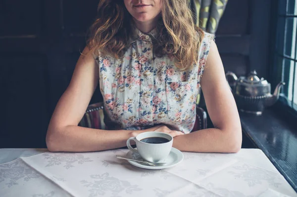 Frau sitzt am Tisch am Fenster und trinkt Kaffee — Stockfoto