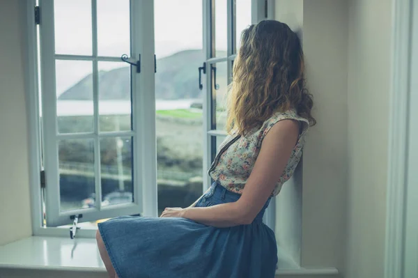 Femme assise près de la fenêtre de la maison rurale — Photo