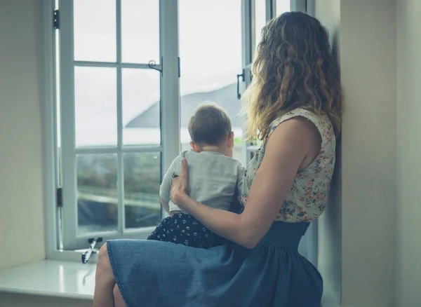 Mother and baby by window of rural home — Stock Photo, Image