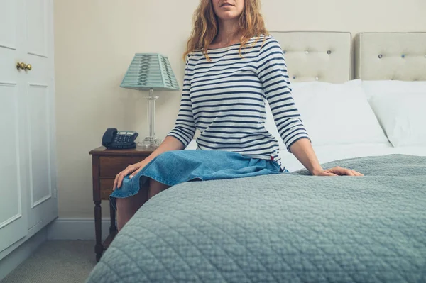ホテルの部屋でベッドの上に座っている若い女性 — ストック写真