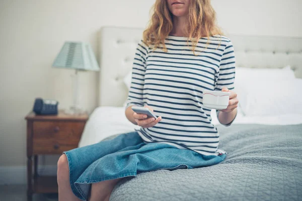 Mujer con taza y teléfono inteligente en la habitación de hotel —  Fotos de Stock