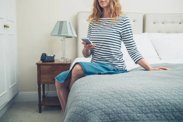 Γυναίκα στο κρεβάτι στο δωμάτιο του ξενοδοχείου χρησιμοποιώντας έξυπνο τηλέφωνο — Φωτογραφία Αρχείου