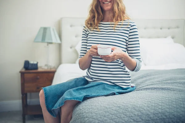 Gelukkige vrouw in hotelkamer met kop — Stockfoto