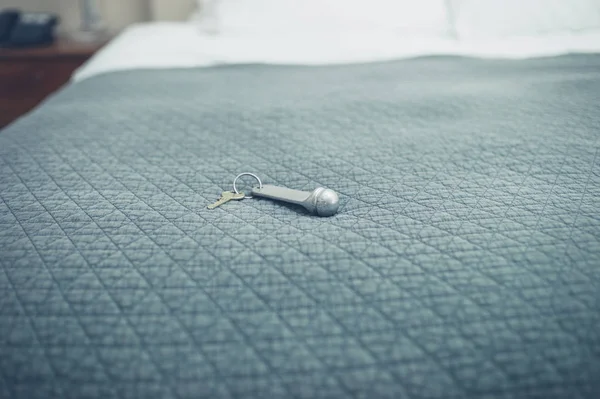 Llave de la habitación del hotel en la cama recién hecha —  Fotos de Stock
