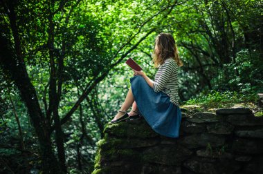 Kadın duvar ormandaki kitap okuma