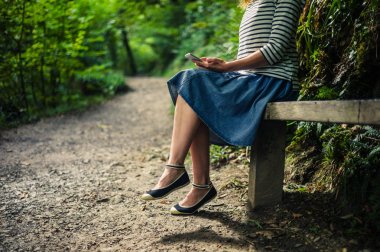 Ormanda akıllı telefon kullanan genç kadın