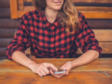 Verandada akıllı telefon kullanan genç kadın