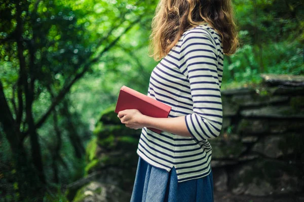 Kvinna med bok stående i skogen — Stockfoto