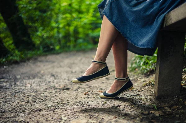 Mujer joven descansando en el banco en el bosque — Foto de Stock