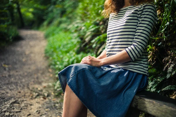 Ormandaki bankta oturan genç kadın — Stok fotoğraf