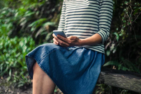 Ung kvinna med smart telefon i skogen — Stockfoto