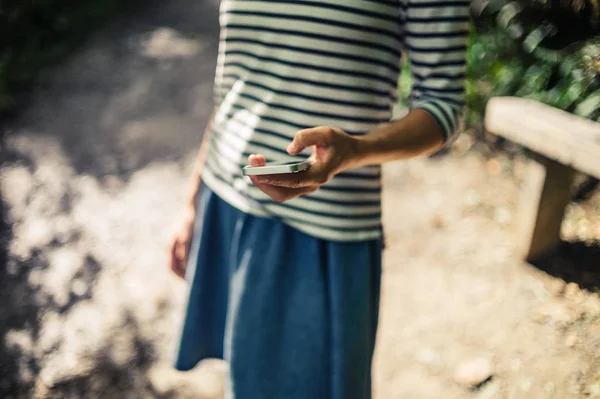 Ormanda akıllı telefon kullanan genç kadın — Stok fotoğraf