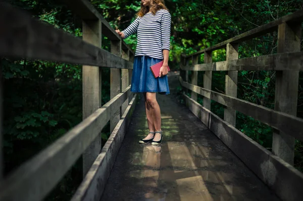 Frau mit Buch auf Brücke im Wald — Stockfoto