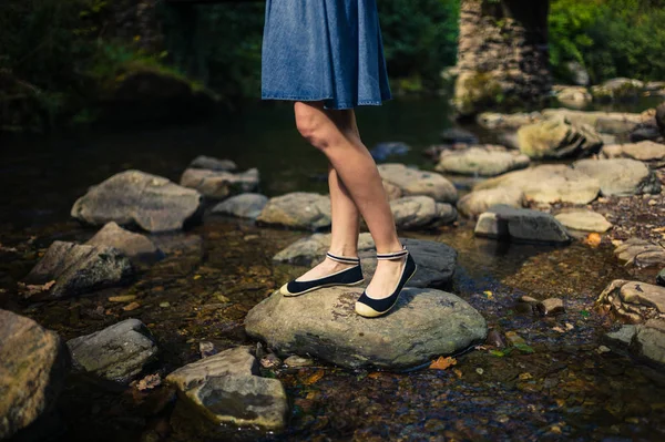 Frau im Rock steht auf Felsen im Fluss — Stockfoto