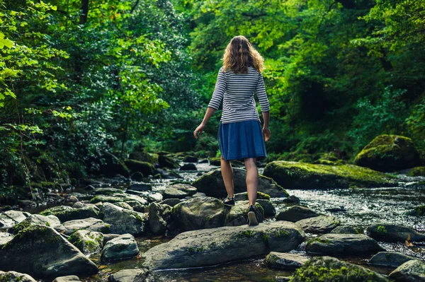 Vrouw lopen op rotsen in de rivier — Stockfoto