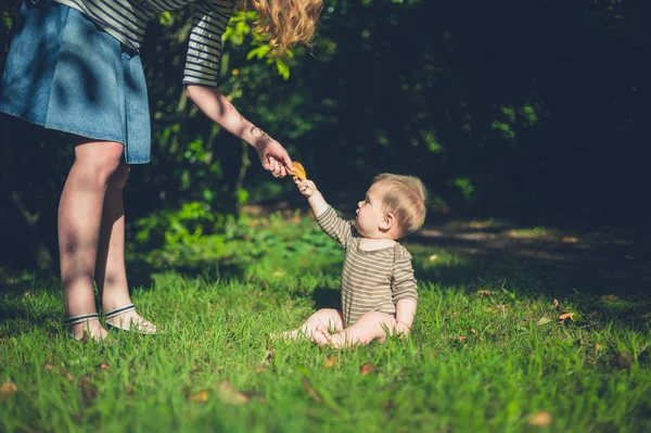 Pequeño bebé en la hierba tomando la mano de la madre — Foto de Stock