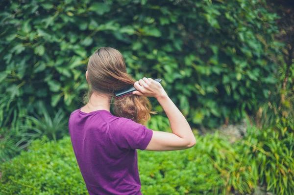 在外面刷她的头发的年轻妇女 — 图库照片