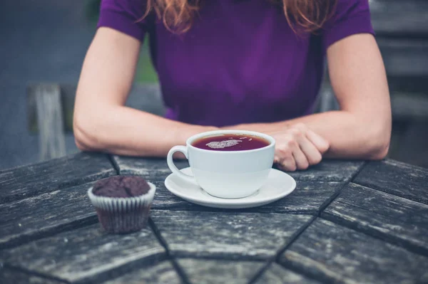 お茶とケーキのカップを持つ女性 — ストック写真