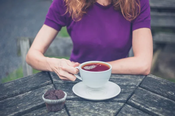 Mulher com xícara de chá e cupcake — Fotografia de Stock