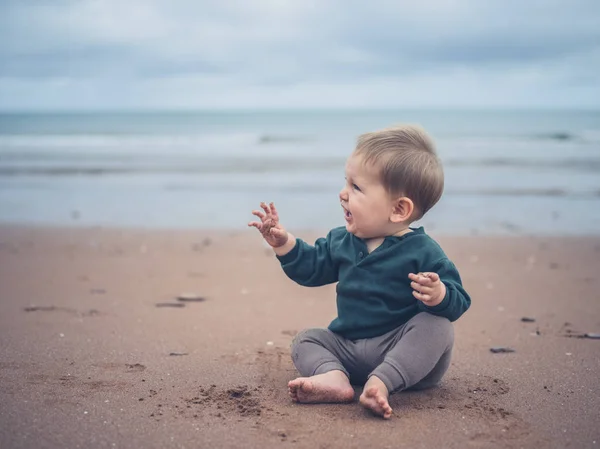 Pequeno bebê sentado na praia — Fotografia de Stock