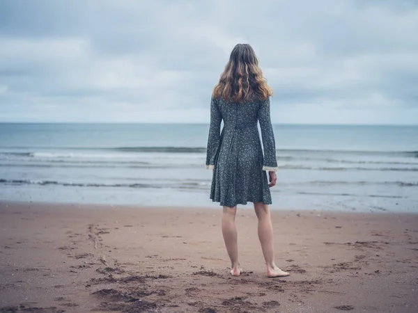 Mulher de vestido admirando o oceano — Fotografia de Stock