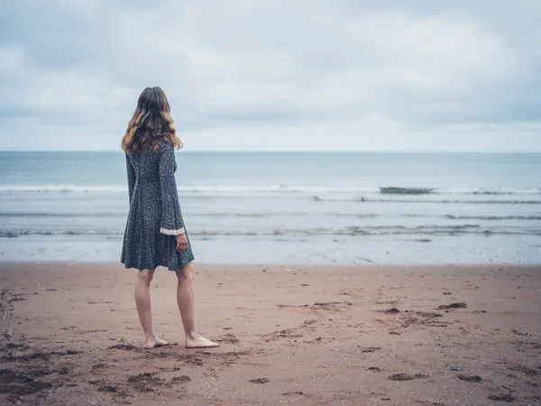 Mulher de vestido admirando o oceano — Fotografia de Stock